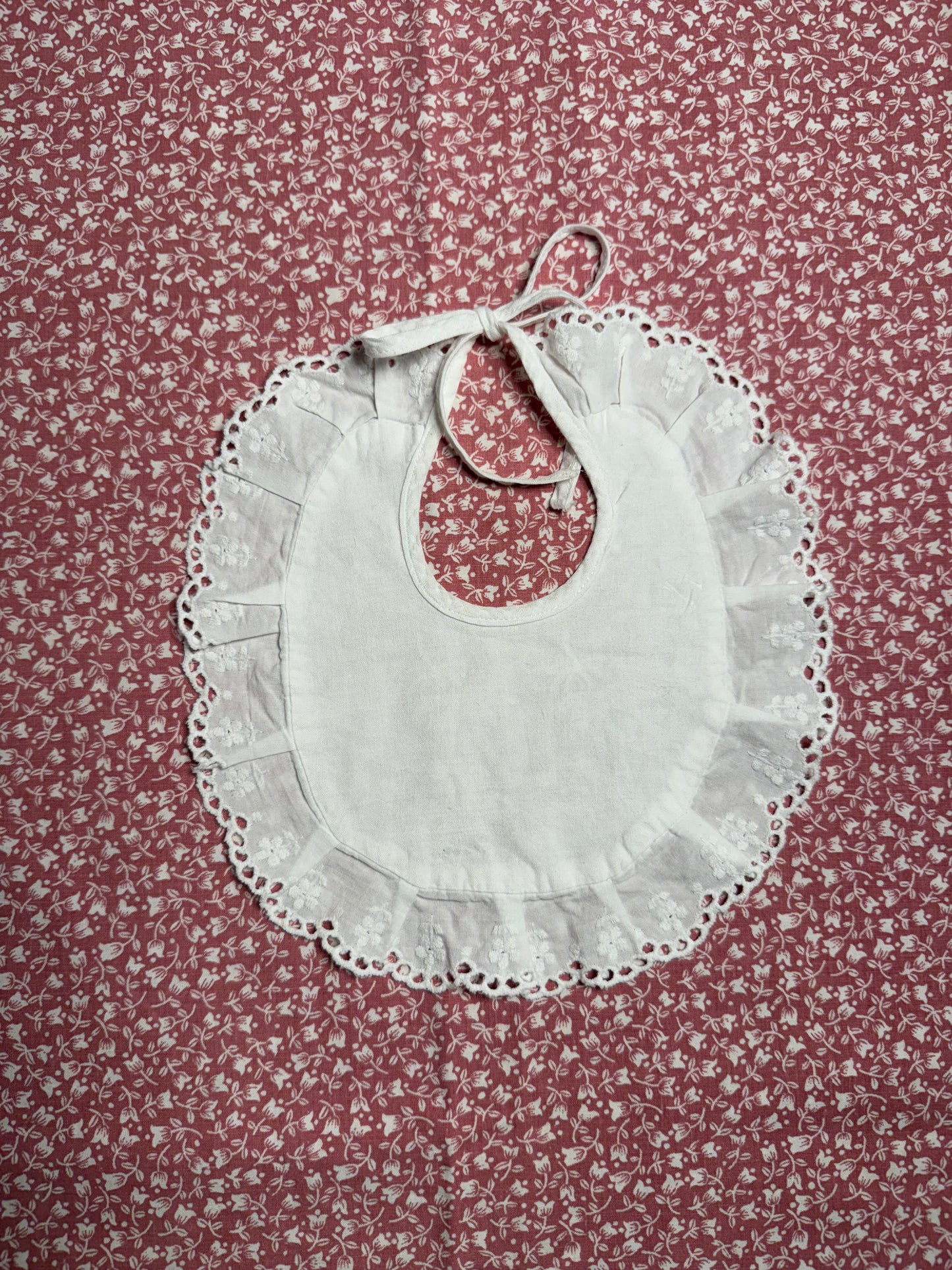 Bavoir ancien de bébé, rond et brodé avec liseré